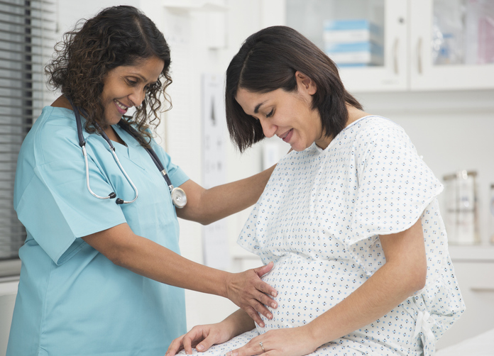 Photo shows a nurse examining a pregnant patient's stomach/Getty Images