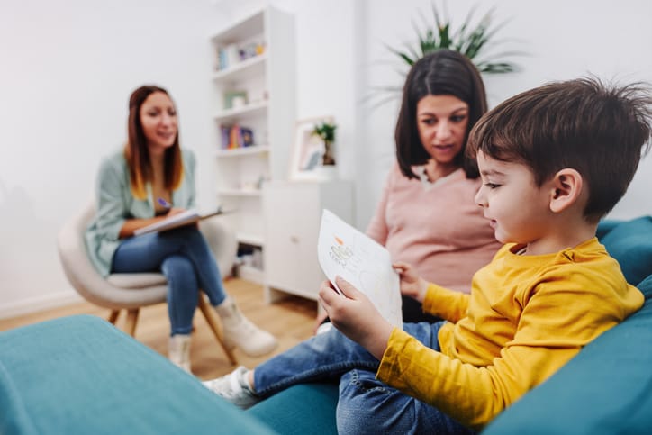 Photo shows a child being evaluated by a psychologist with his mother present/Getty Images