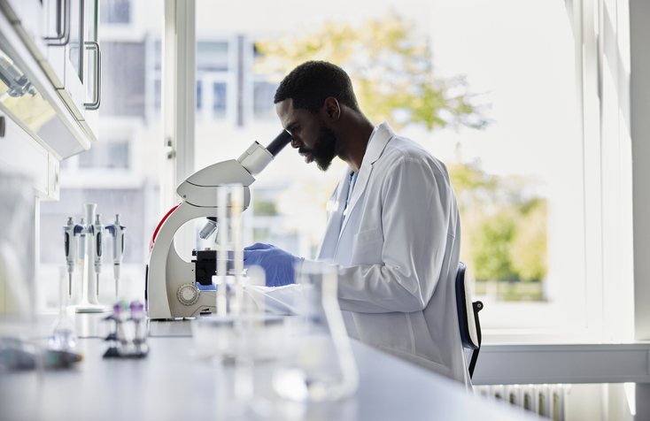 Photo shows a scientist looking into a microscope/Getty Images