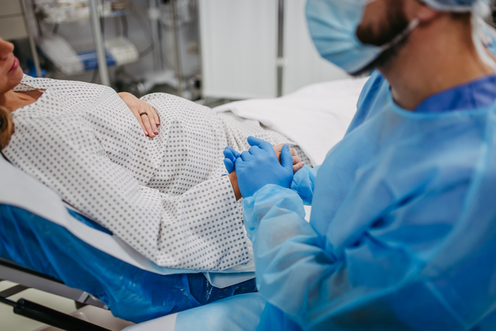 Photo shows a man holding a pregnant woman's hand while she gives birth/Getty Images