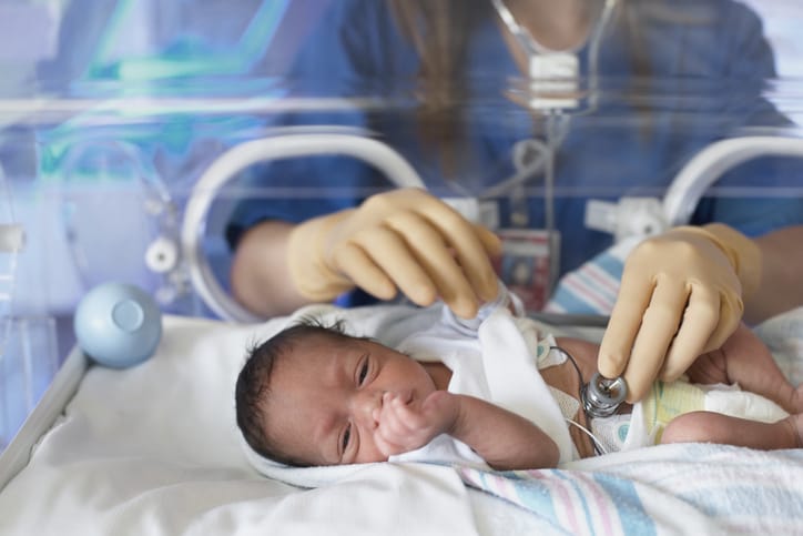 Photo shows a female doctor examining newborn baby in incubator/Getty Images