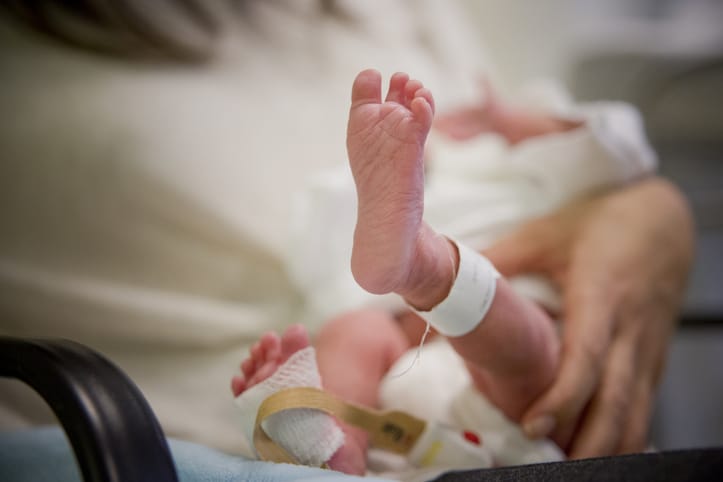 Photo shows an adult holding a premature newborn baby/Getty Images